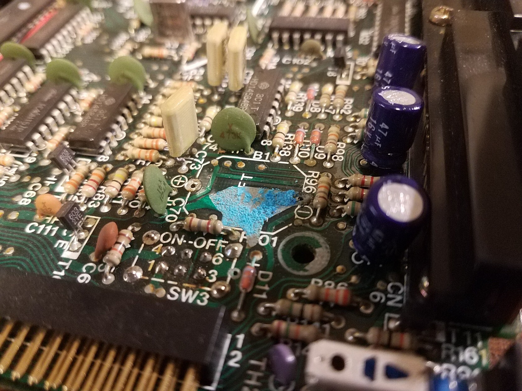 A PCB board with blue copper corrosion on a copper trace that is normally protected by solder mask. The battery leakage got underneath the solder mask and destroyed the traces.